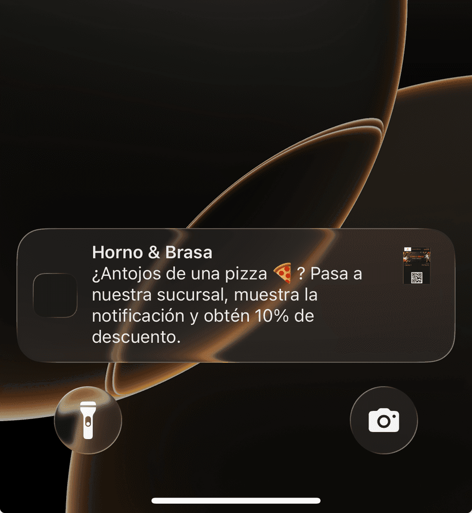 Pantalla de bloqueo de un iPhone con una notificación de una pizzería que ofrece 10% de descuento a quien pase por la sucursal